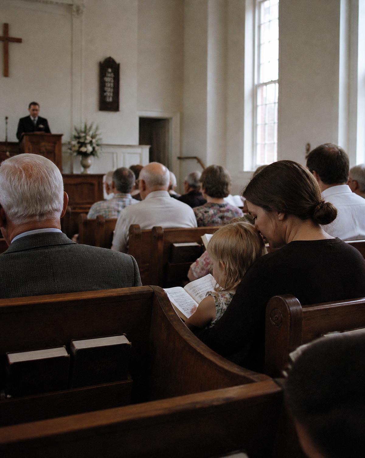 A congregation seated together during Sunday worship, including a parent and young child